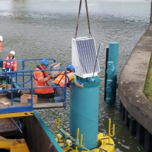 De kraan laat de zonnepanelen op de paal zakken en de monteur in de mobile hoogwerker zet deze vast met bouten De kraan laat de zonnepanelen op de paal zakken en de monteur in de mobile hoogwerker zet deze vast met bouten